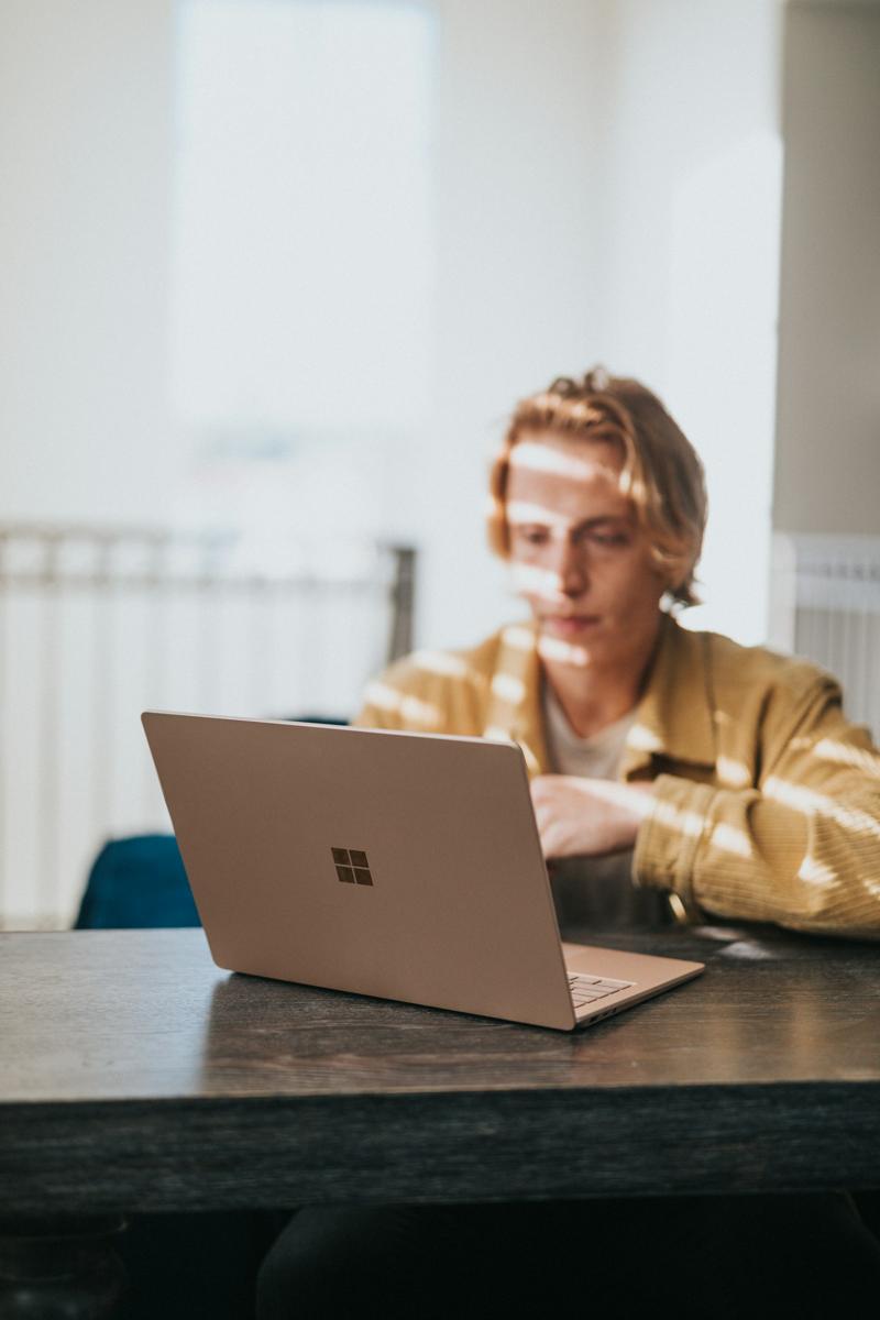 A secondary student working on his laptop in the afternoon sun